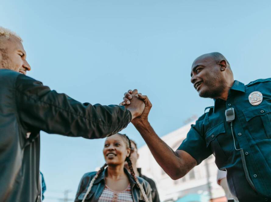A friendly handshake between a police officer and a civilian during an outdoor community event.
