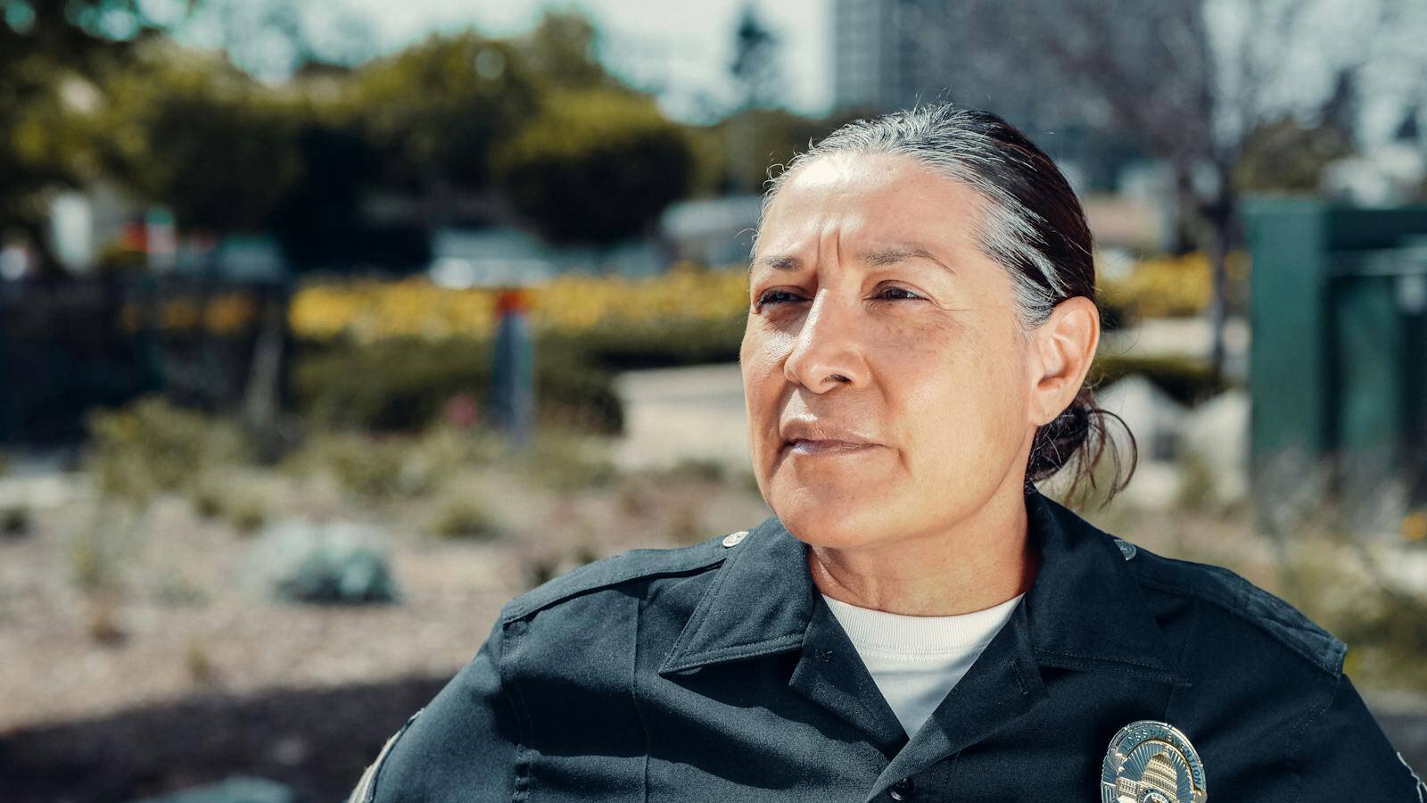 Portrait of a female police officer standing confidently outdoors in uniform.